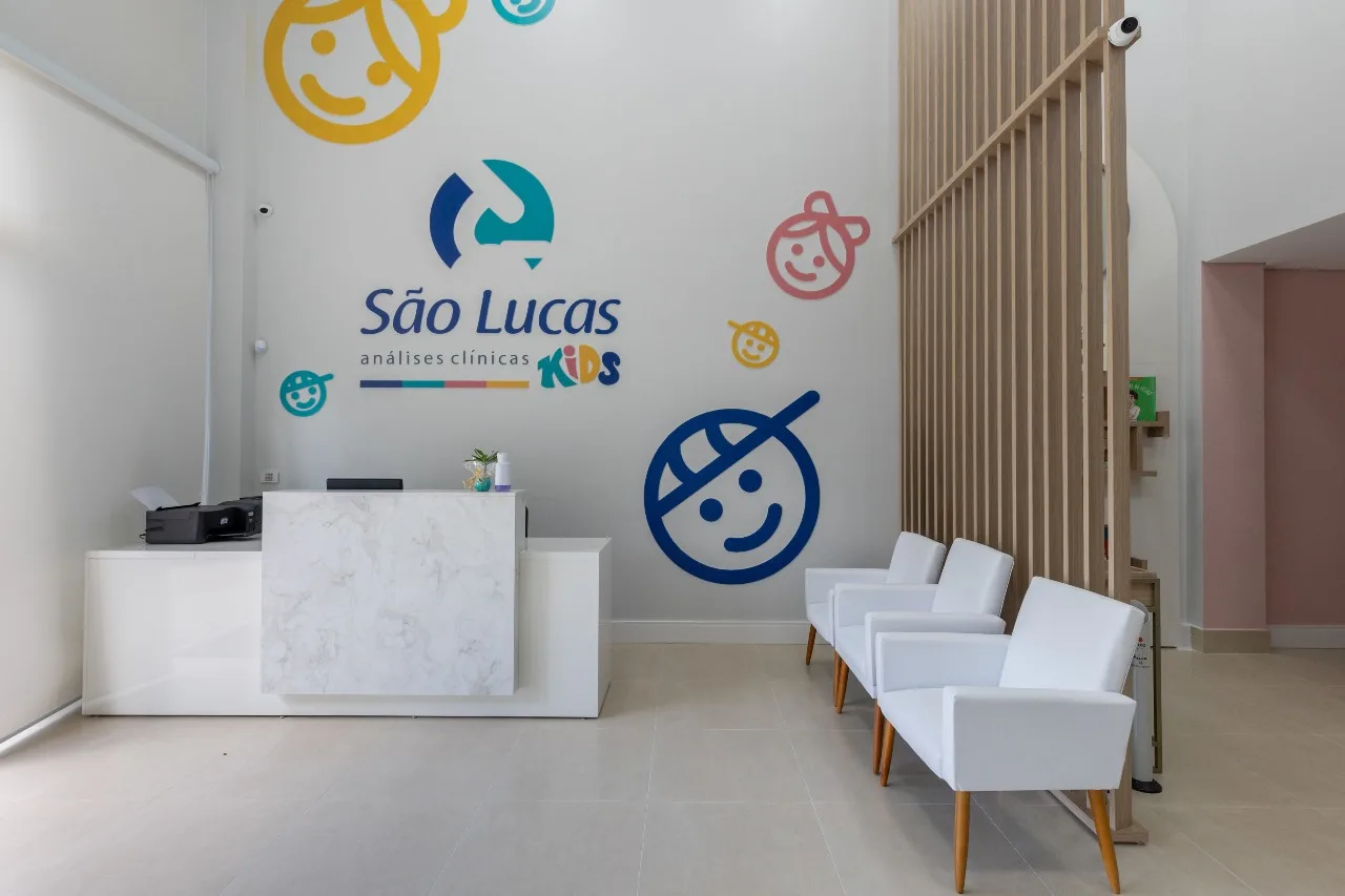 Recepção do São Lucas Kids, com balcão de mármore e a marca infantil na parede